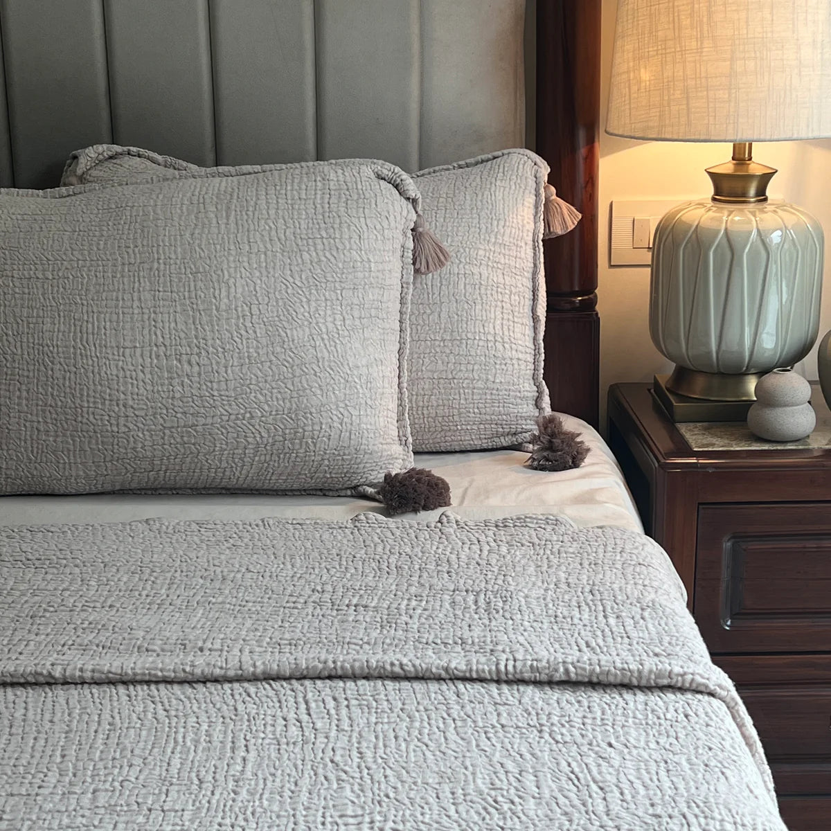 Textured buff woven bedspread and cushions on a made bed.