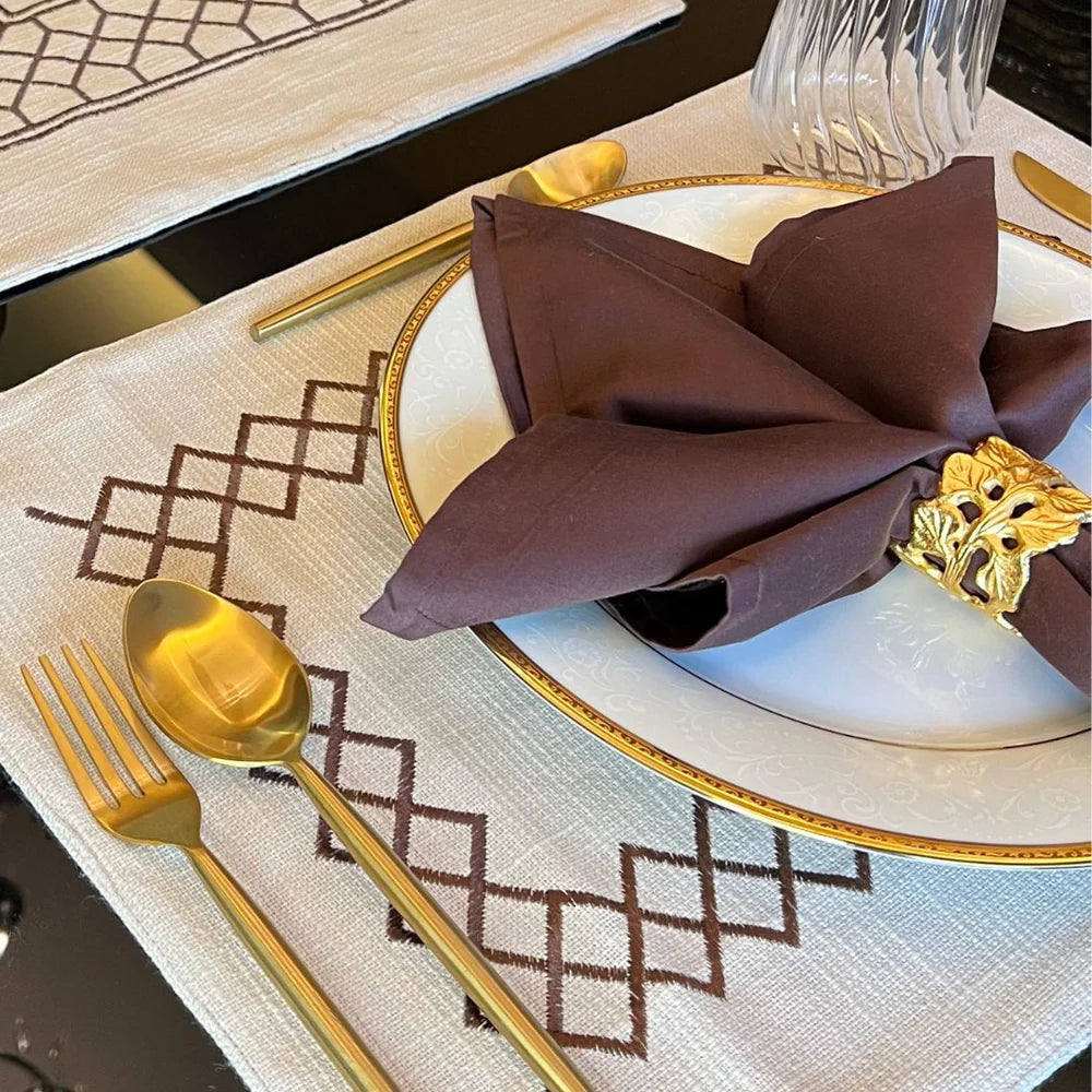 Beige table linen set with zigzag pattern and golden cutlery.